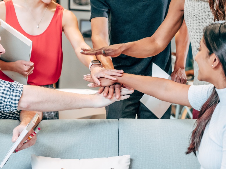 an office staff all putting their hands together to say go team