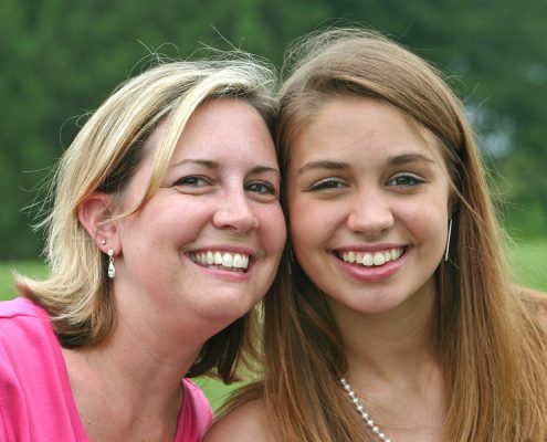 Mother side by side smiling with daughter